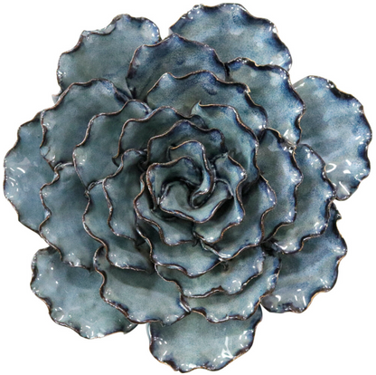Large blue and teal ceramic ocean wall flower styled on a surface with other decorative flowers.
