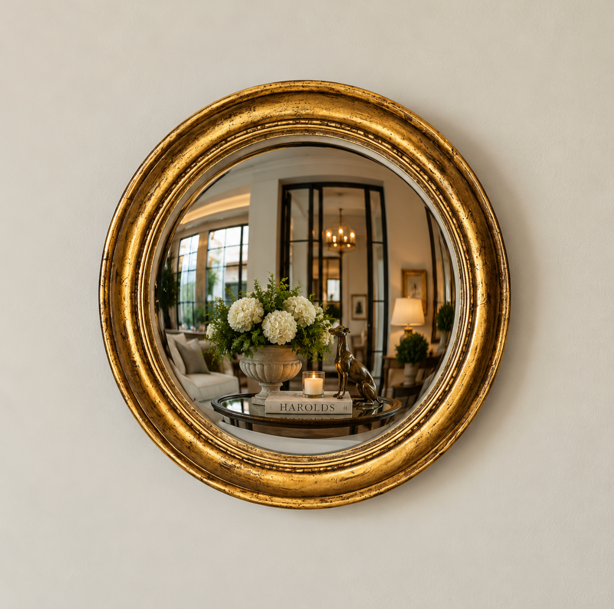Round gold painted timber convex mirror with a vintage finish on a neutral wall