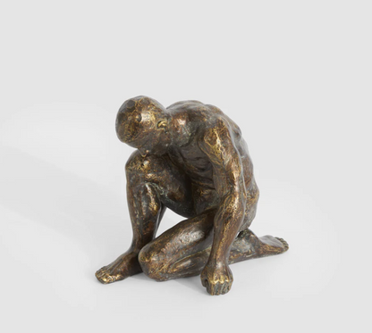Resting man sculpture in antique finish viewed from the rear