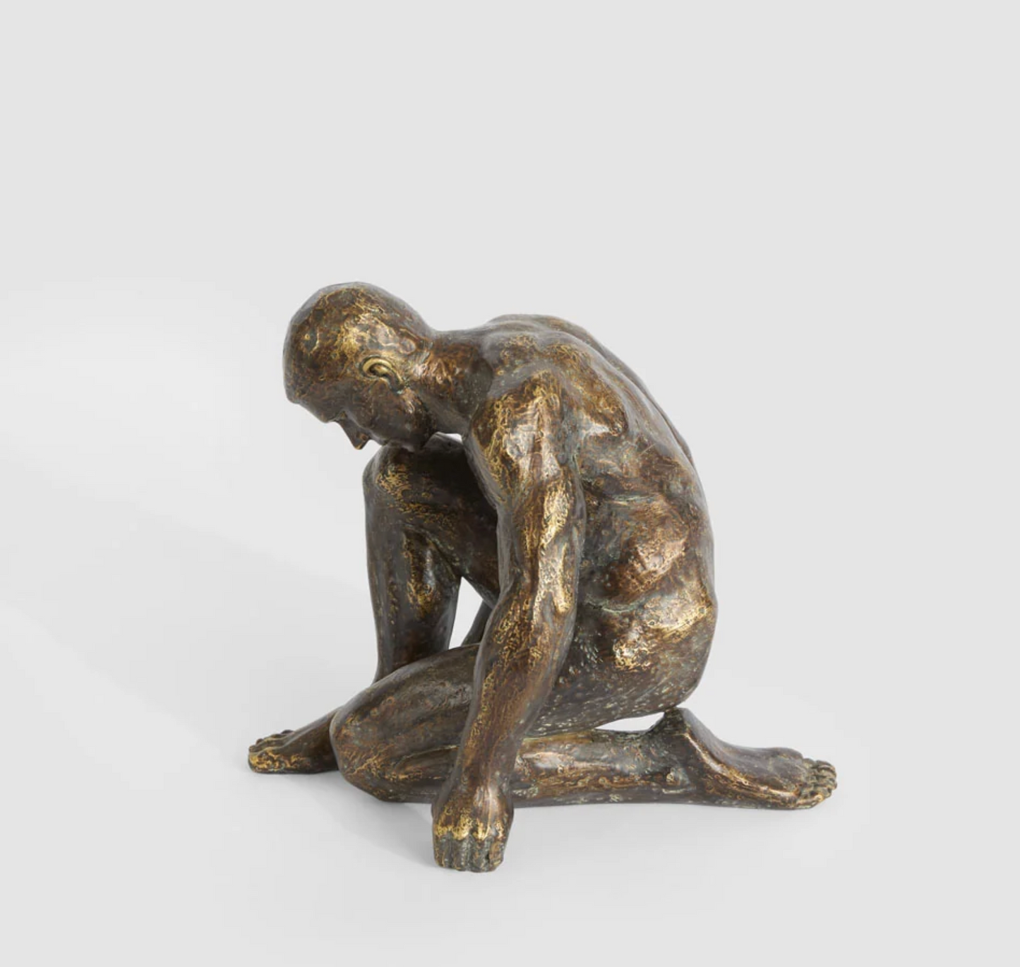 Resting man sculpture in antique finish viewed from the side