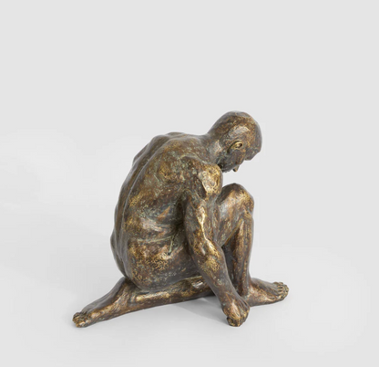 Resting man sculpture in antique finish viewed from the front side