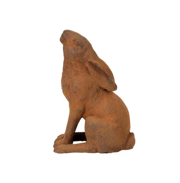 Rust-finished cast iron sitting hare with ears down displayed in a flower garden