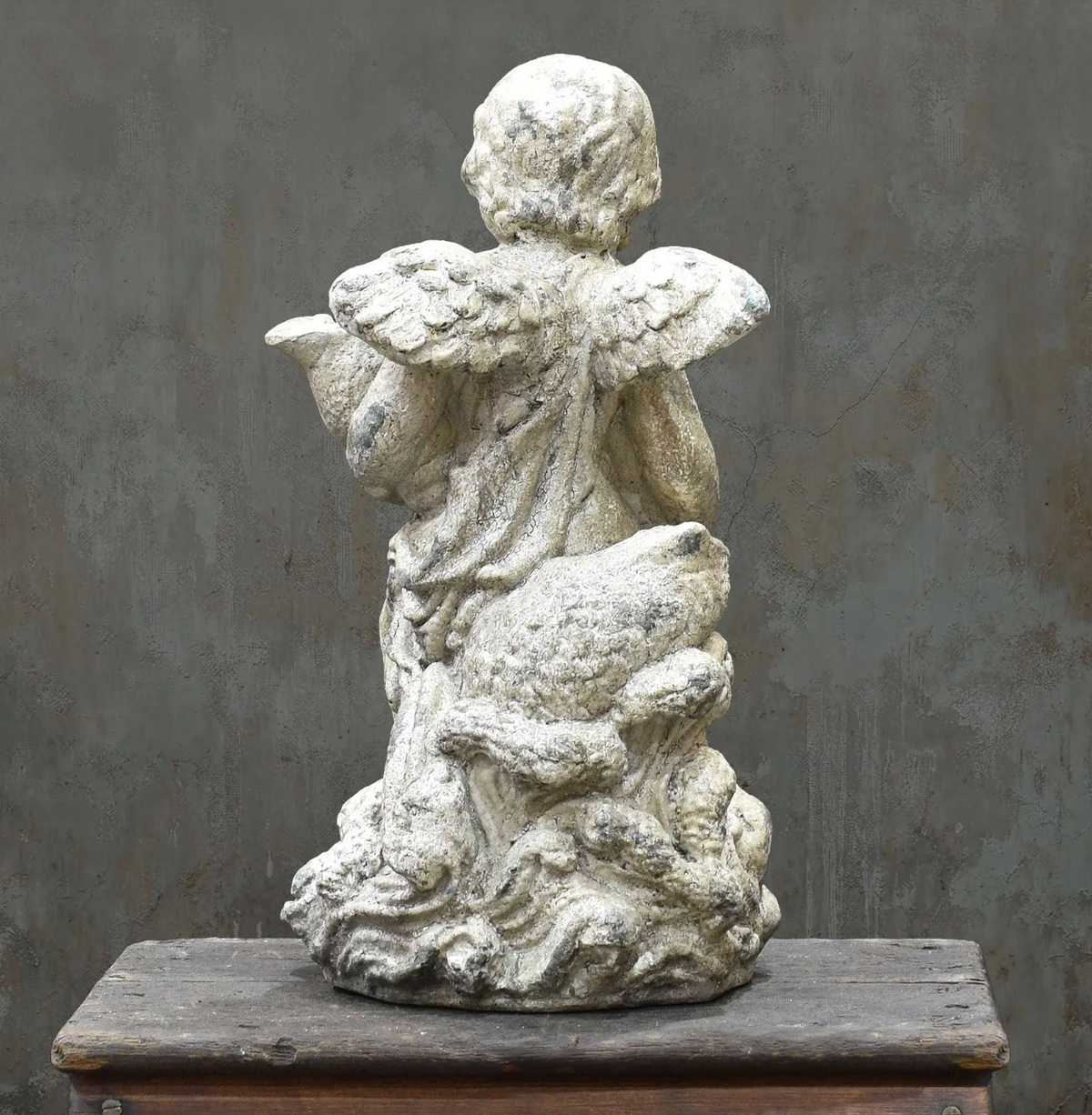 Cherub statue holding drapery, side view