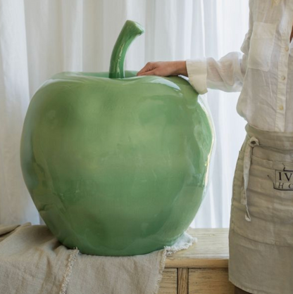 Large glossy green apple ornament beside a person for scale