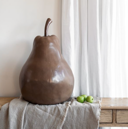 Large brown ceramic pear held sideways by a person to show its scale
