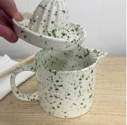 Green speckled juicer with reamer fitted on pouring jug beside a lime