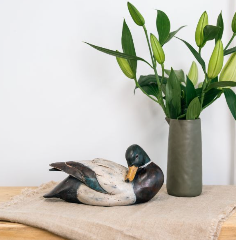 Side view of seated mallard duck sculpture with patterned wings and green head