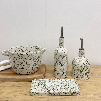 Close view of white pouring bowl with green speckles, handle and spout