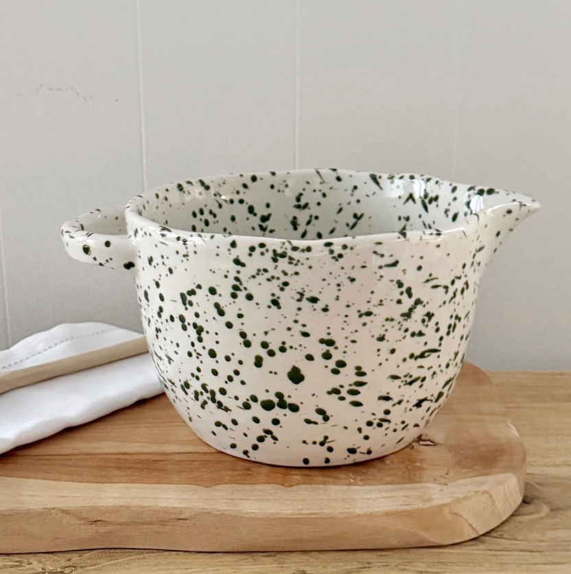 Green speckled pouring bowl with matching kitchen pieces displayed nearby