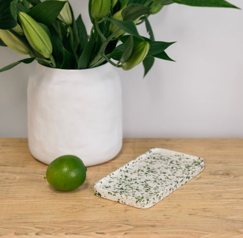 Low side view of rectangular white tray with green splatter and raised rim