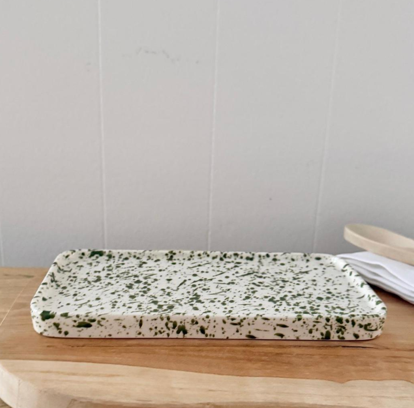 Green splatter tray beside a lime on a wooden table