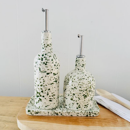 Green splatter tray holding two matching oil pourers