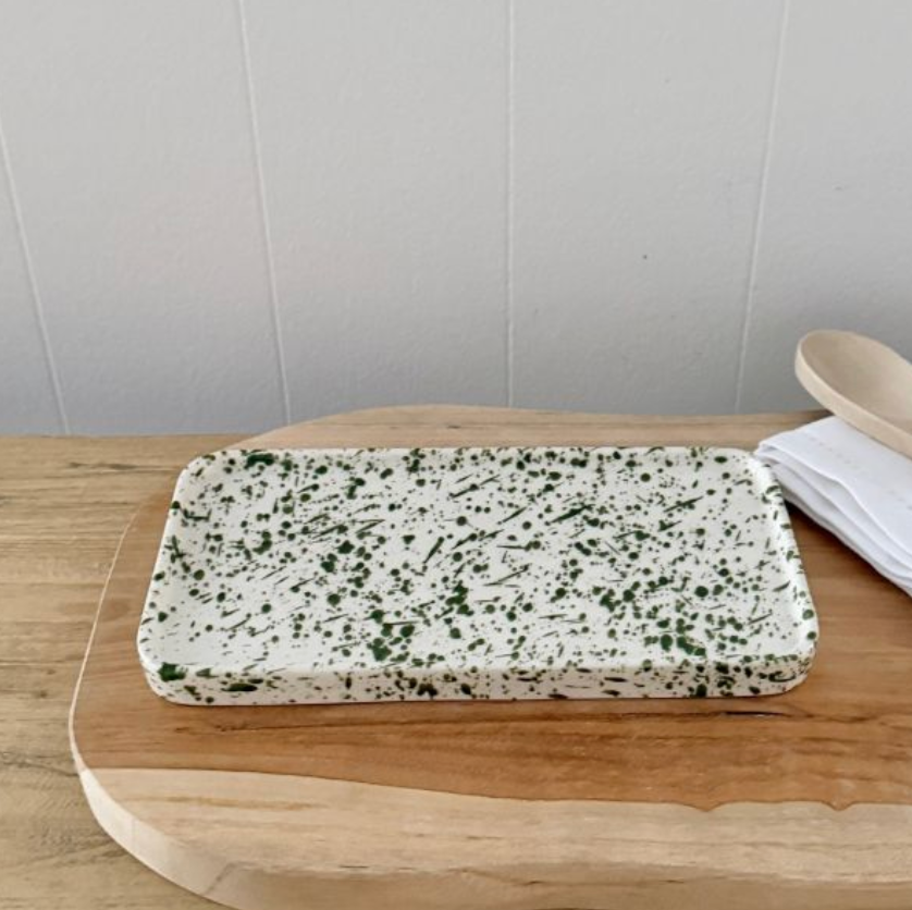 Rectangular white tray with green splatter on a wooden surface