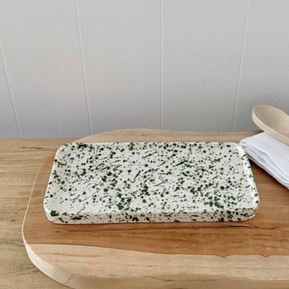 Rectangular white tray with green splatter on a wooden surface
