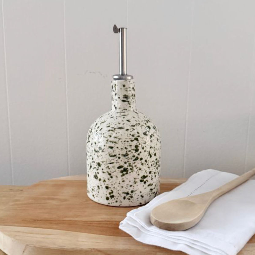 Two green splatter pourer bottles of different shapes displayed on matching tray