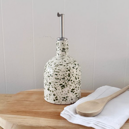 Two green splatter pourer bottles of different shapes displayed on matching tray