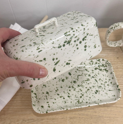 Green splatter butter dish with lid beside a lime and vase