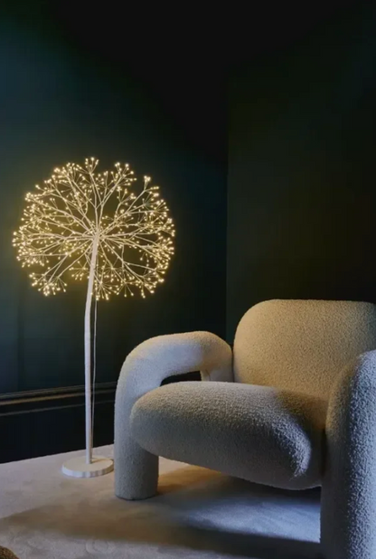 White dandelion tree light with warm white LEDs beside an upholstered chair