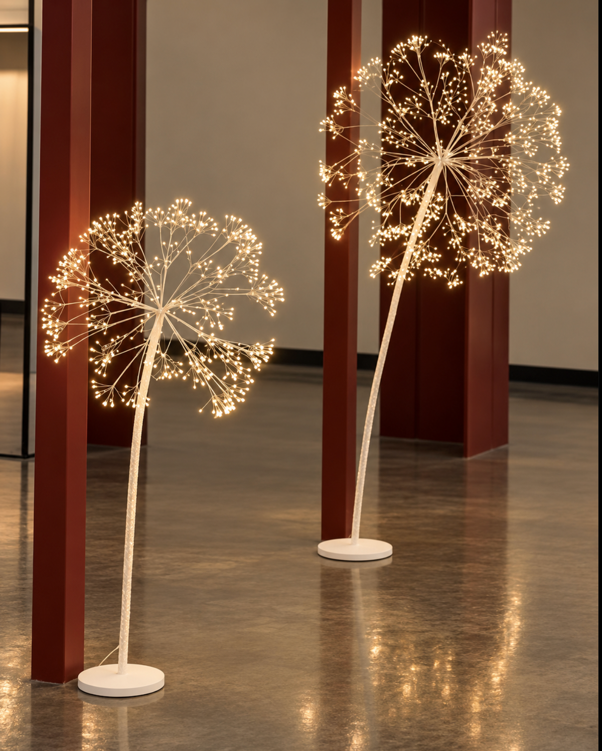 Two white dandelion tree lights glowing indoors, shown in different sizes