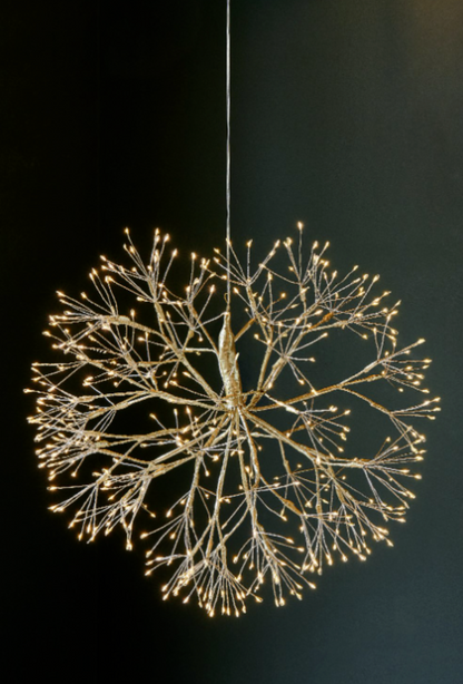 Two hanging dandelion lights beside a pendant lamp in a dark interior