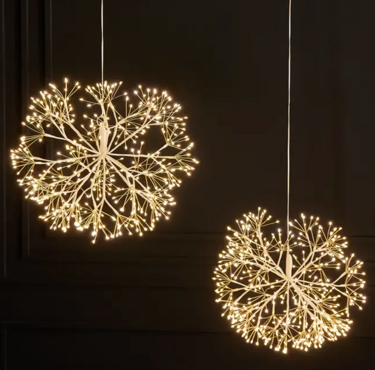 Two glowing hanging dandelion lights above a decorative horse indoors