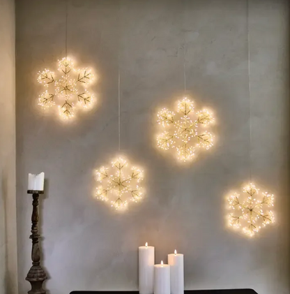 Several glowing snowflake hanging lights displayed above a fireplace