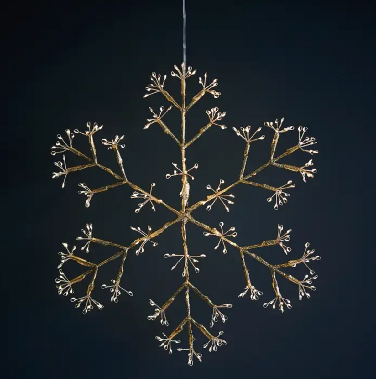 Three illuminated snowflake hanging lights above a fireplace