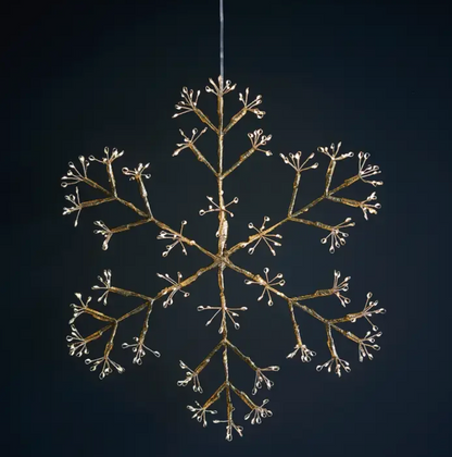 Three illuminated snowflake hanging lights above a fireplace