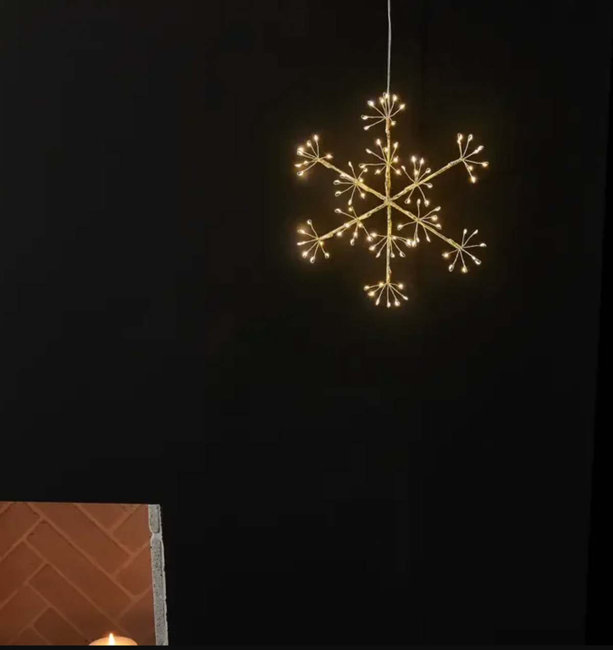 Glowing six-point snowflake hanging light against a pale wall