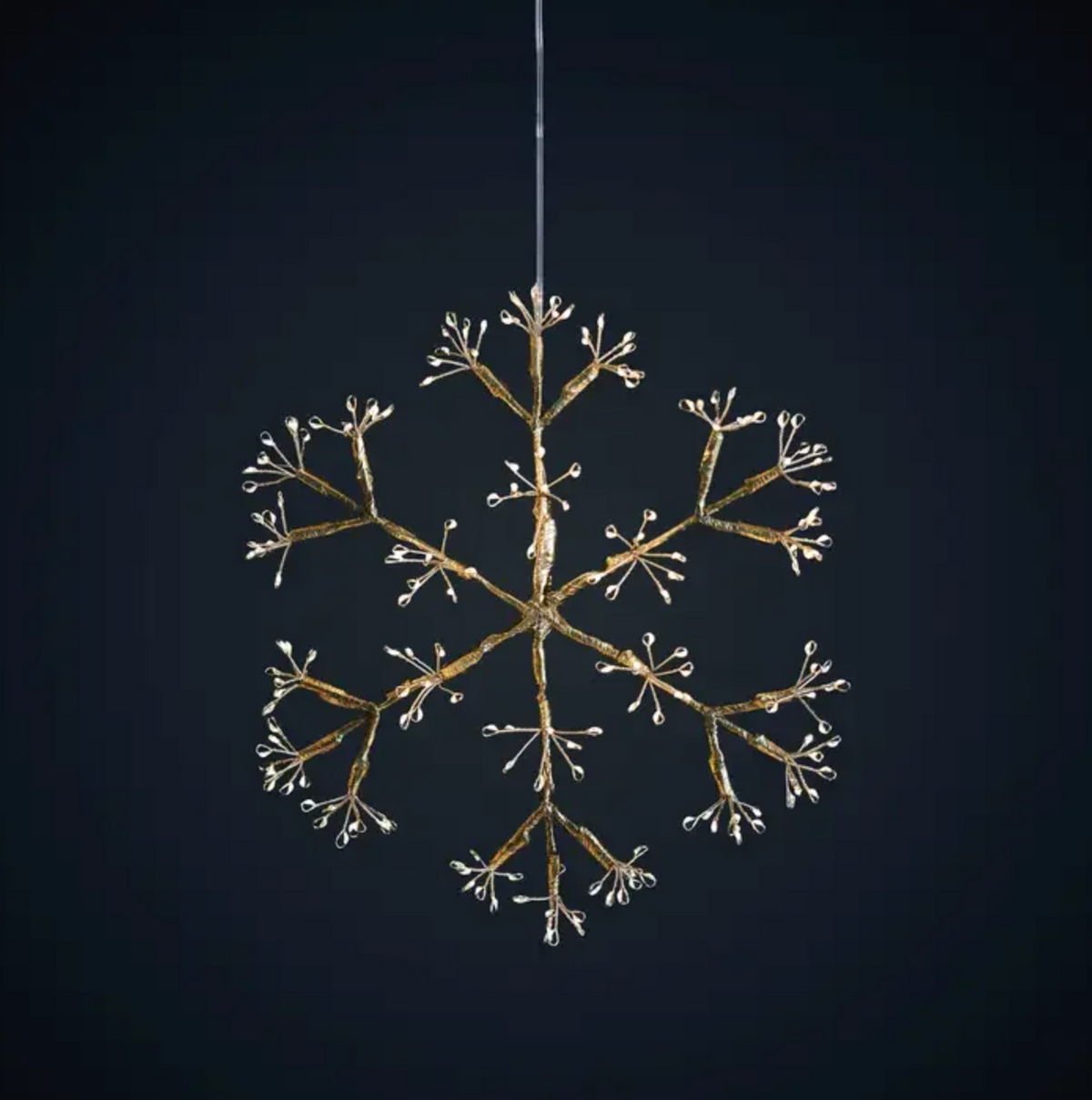 Four glowing snowflake hanging lights displayed above candles