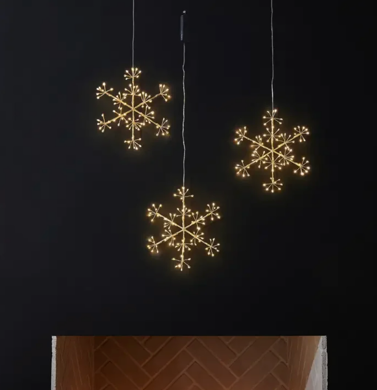 Illuminated snowflake hanging ornament against a dark wall
