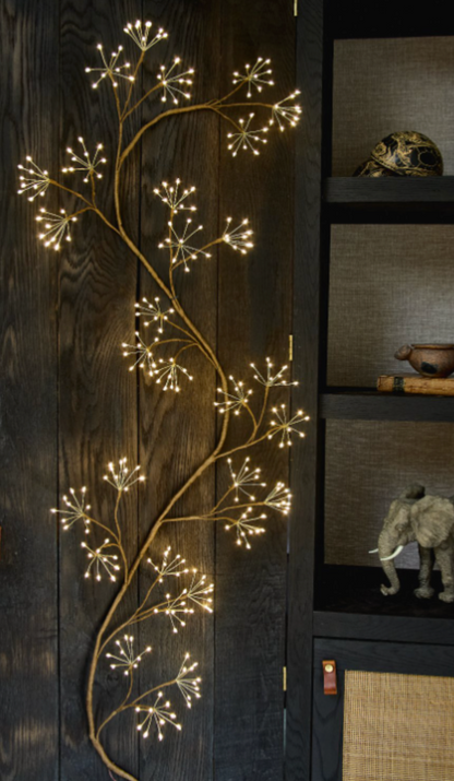 Brown branching ivy-inspired light with glowing tips arranged vertically indoors