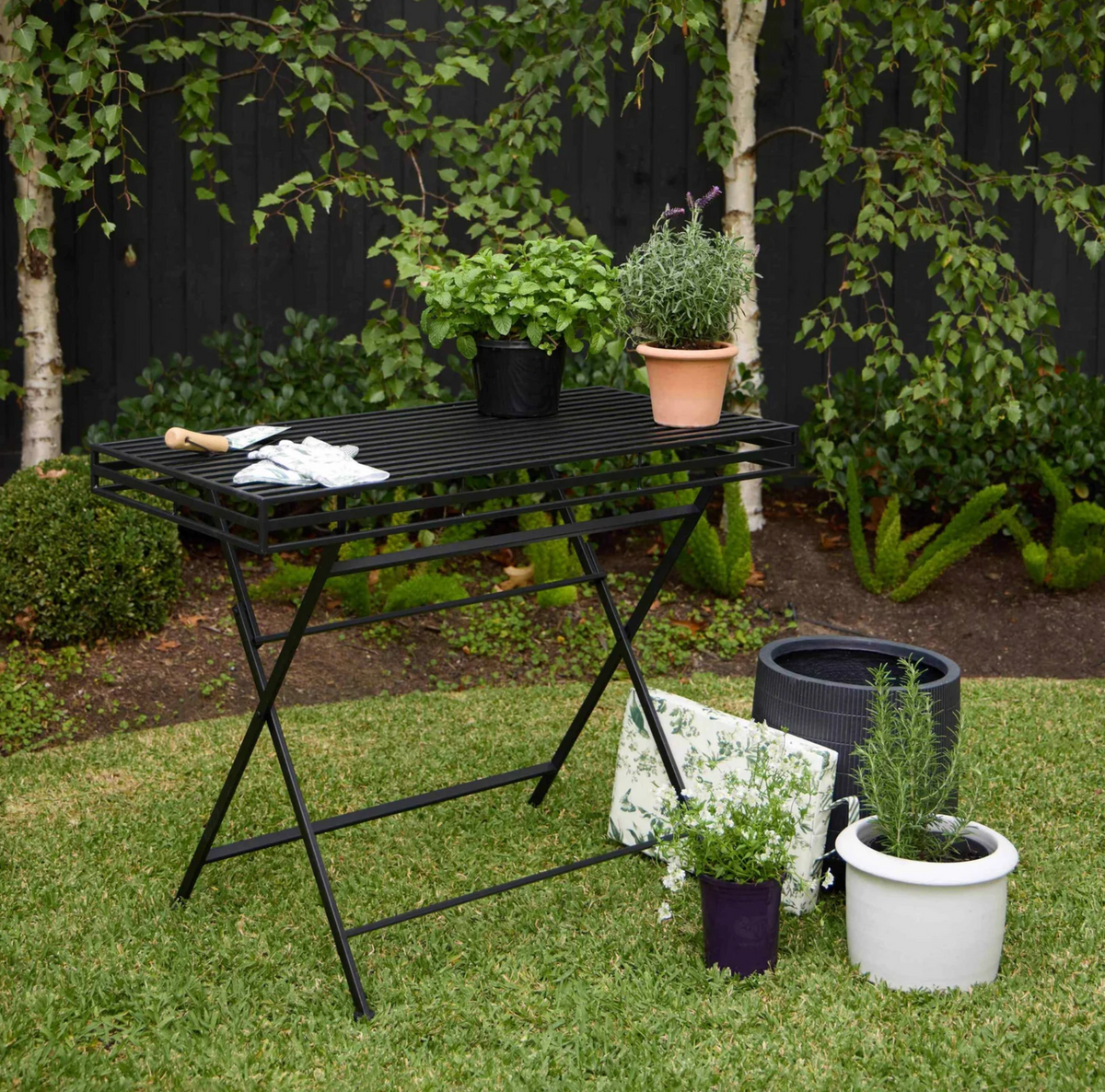Black iron garden table with slatted rectangular top against a white background