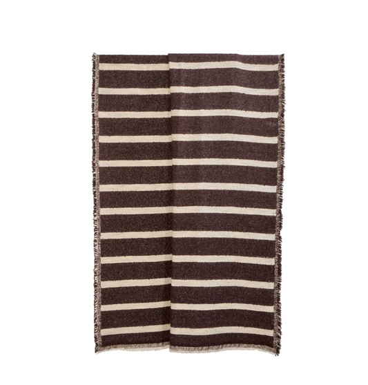 Brown and natural striped throw draped over a brown chair in a living room
