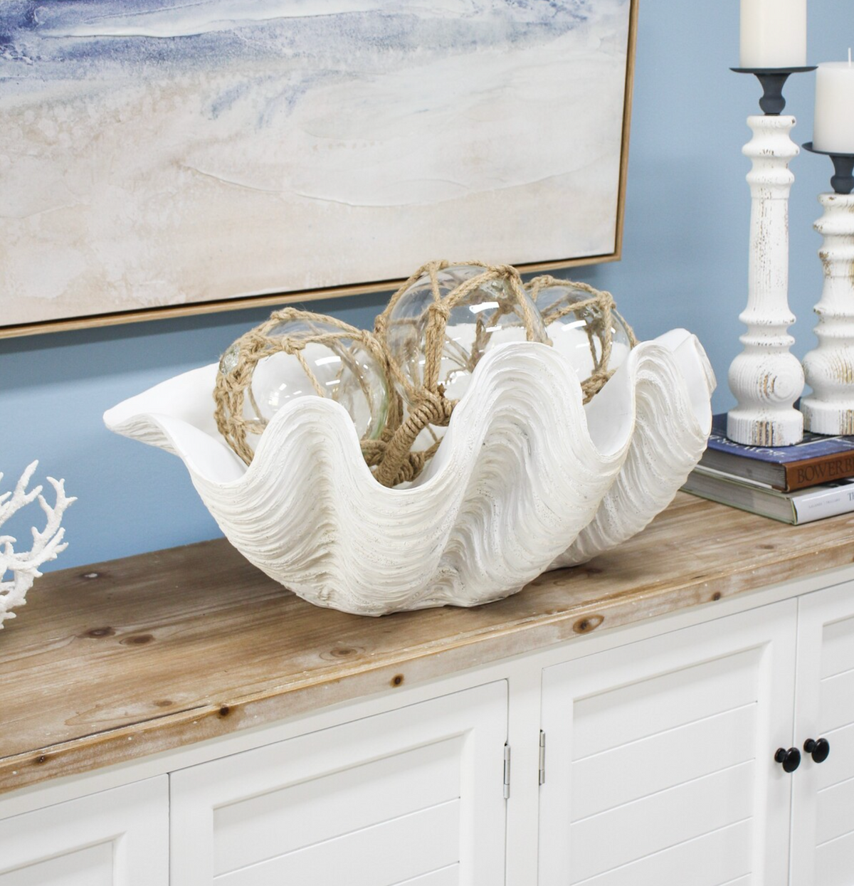 Giant white clam shell styled with rope-wrapped glass floats on a wooden-topped cabinet