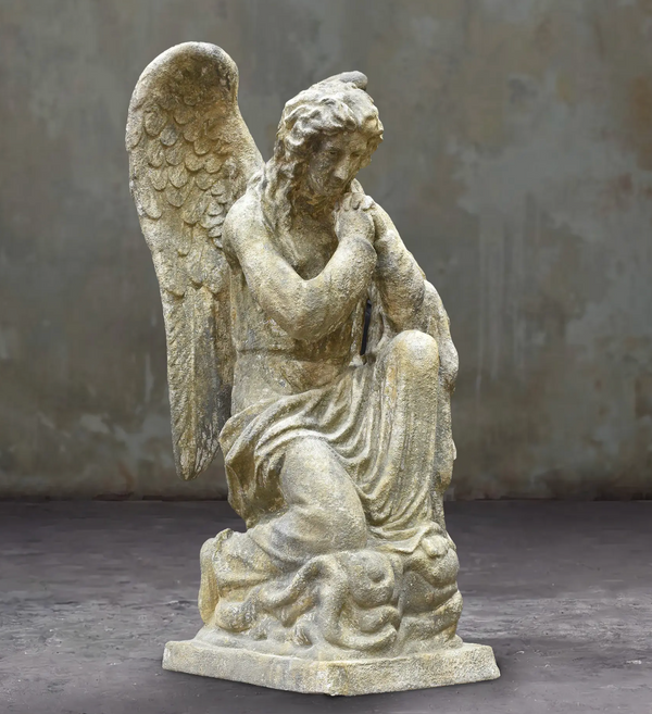 Kneeling angel statue with clasped hands, feathered wings and a weathered stone finish