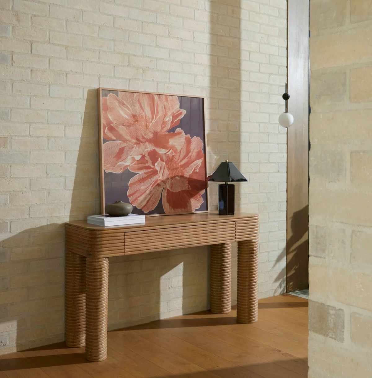 Brown faceted table lamp styled on a console beside framed floral artwork