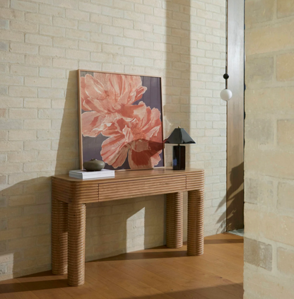 Brown faceted table lamp styled on a console beside framed floral artwork