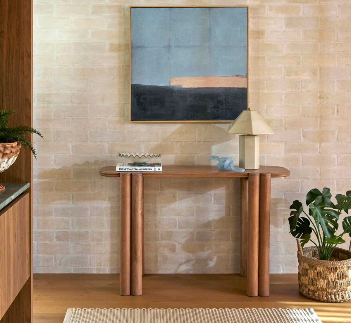 Ivory faceted table lamp on a wooden console beneath framed abstract artwork