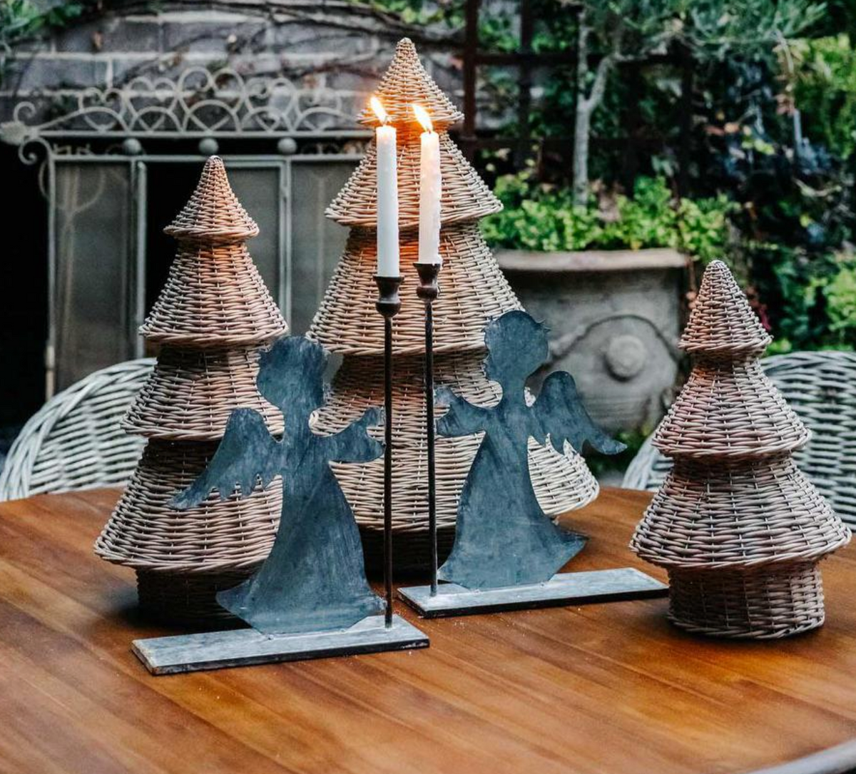 Three willow Christmas trees styled on a wooden table with angels and candles