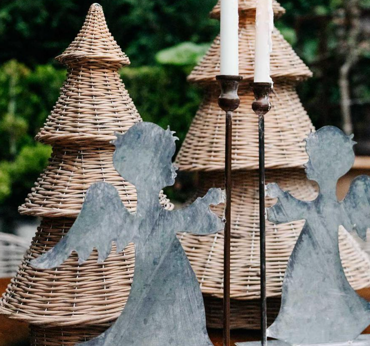 Close-up of willow Christmas trees behind metal angel decorations