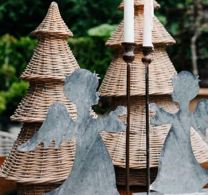 Close-up of willow Christmas trees behind metal angel decorations