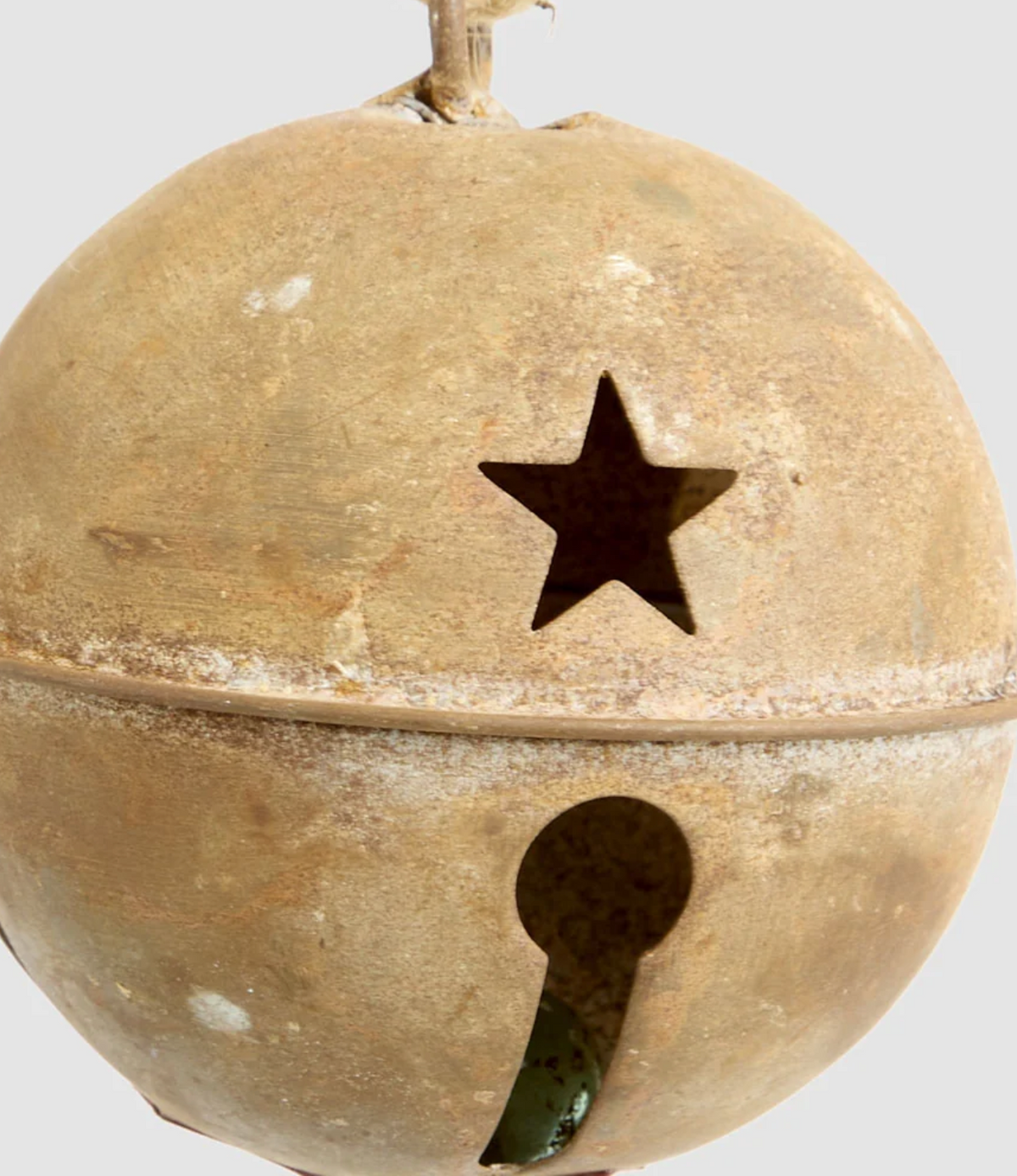 Close-up of rusty bell bauble showing star cut-out and rounded metal surface