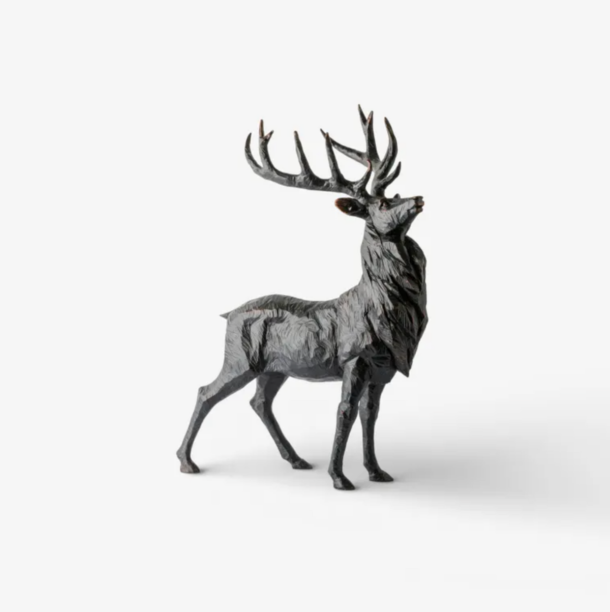 Antique black stag sculpture standing with its head raised and branching antlers
