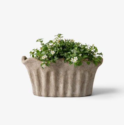 Terra Fluted Oval Planter Small in sand terracotta with a flowering plant