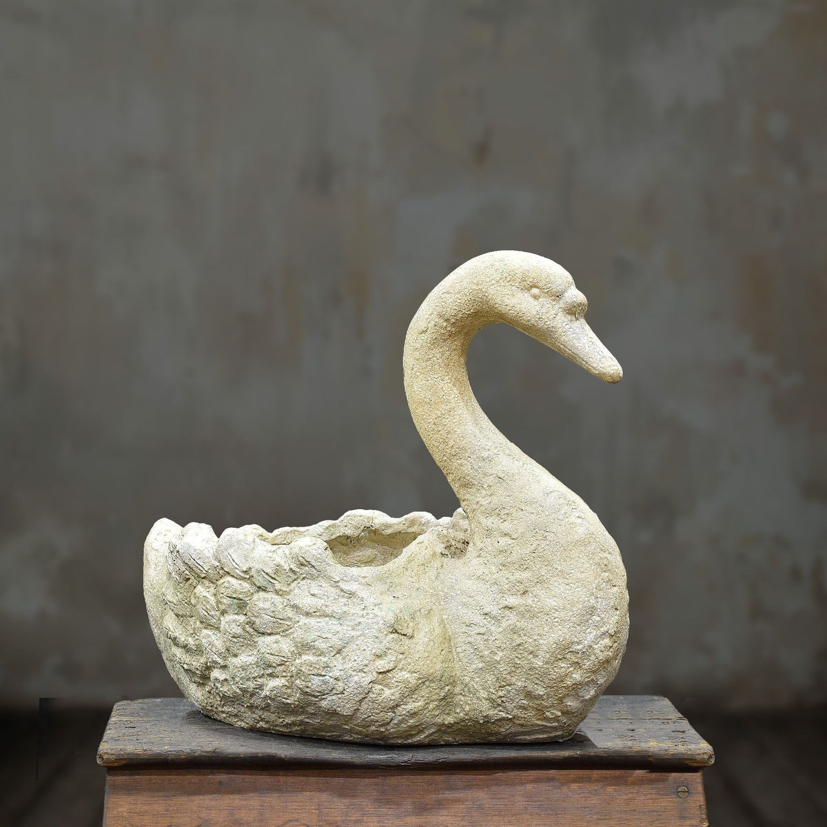 Cement swan planter with curved neck and weathered cream finish, side view