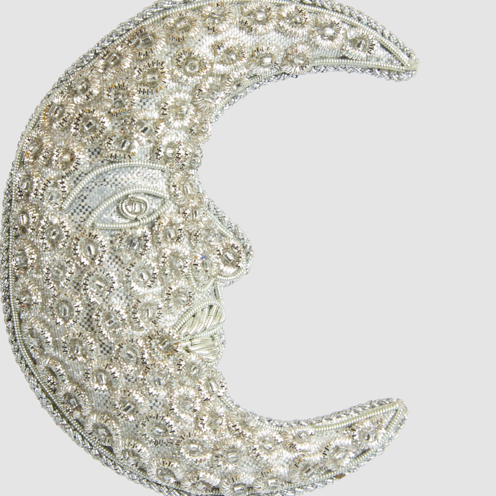 Close-up of the silver crescent moon showing the face and intricate floral embellishments