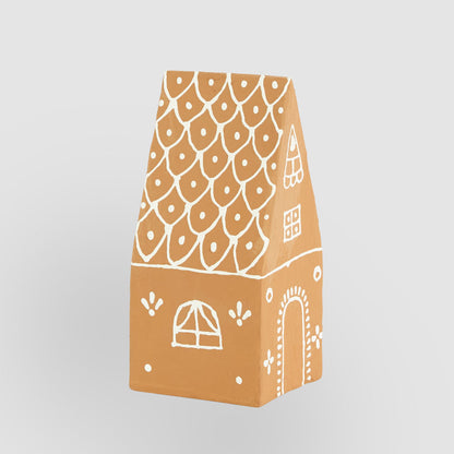 Angled view of the pitched-roof gingerbread house showing white scalloped roof pattern and side window