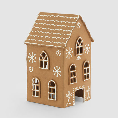 Angled view of the tall gingerbread house showing arched windows and white snowflake-style decoration