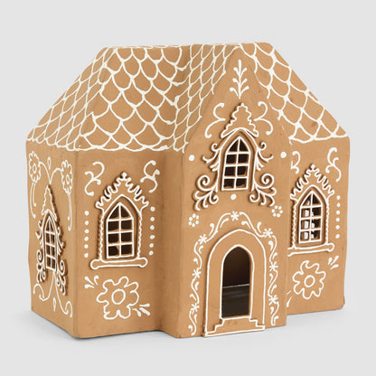 Front angled view of the large gingerbread house showing scalloped roof lines and decorative window surrounds